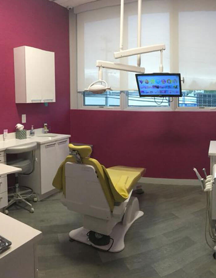 dental examination room with white and red exam chair, red walls, and video monitor