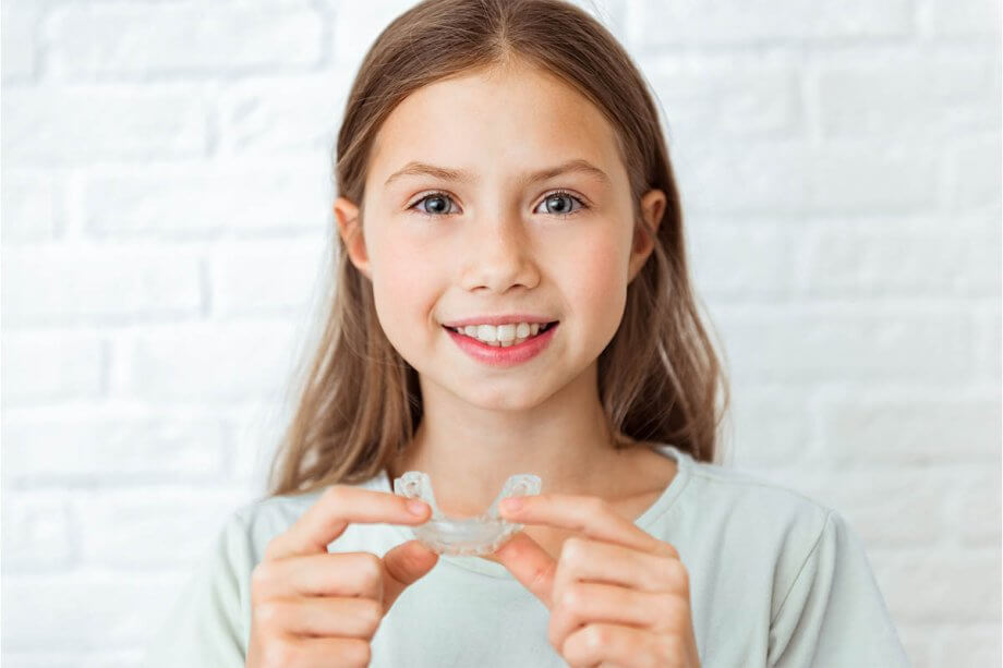 Child holding invisalign smiling