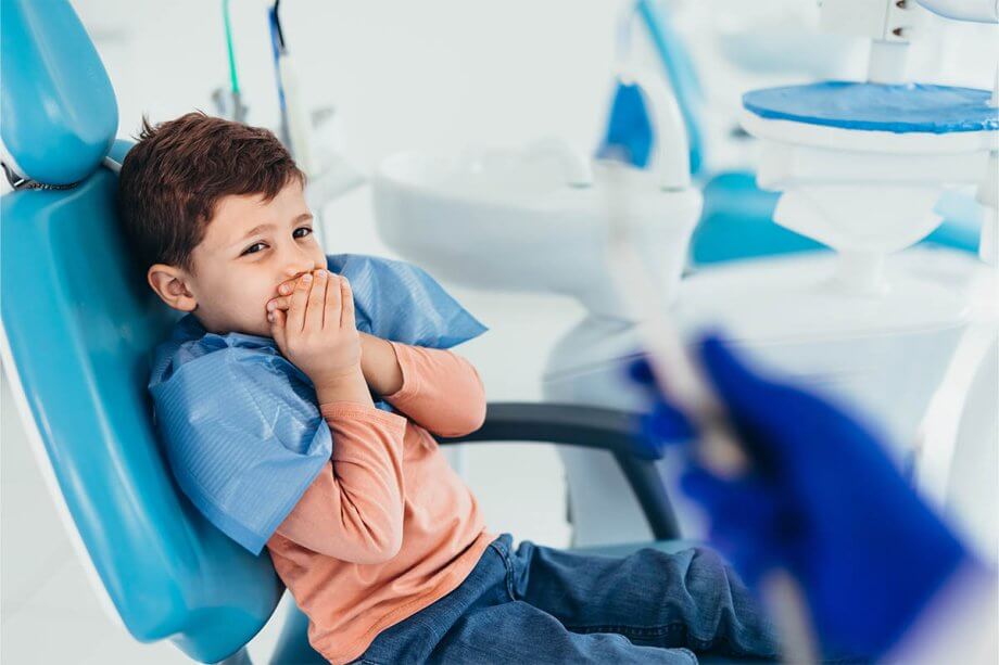 Child holding mouth in dentist