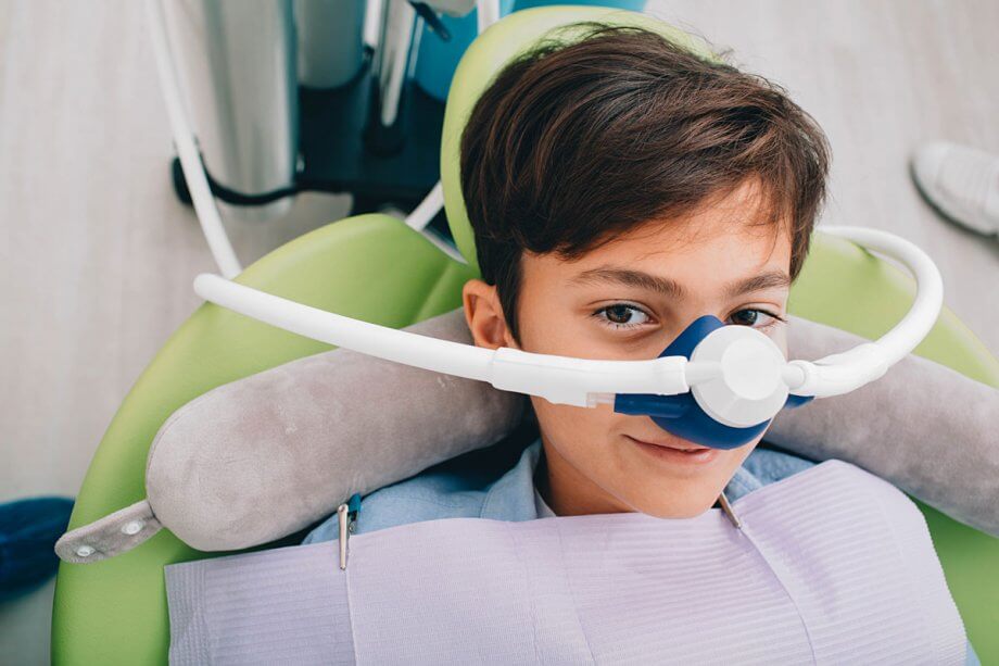 child in dental chair wears sedation mask