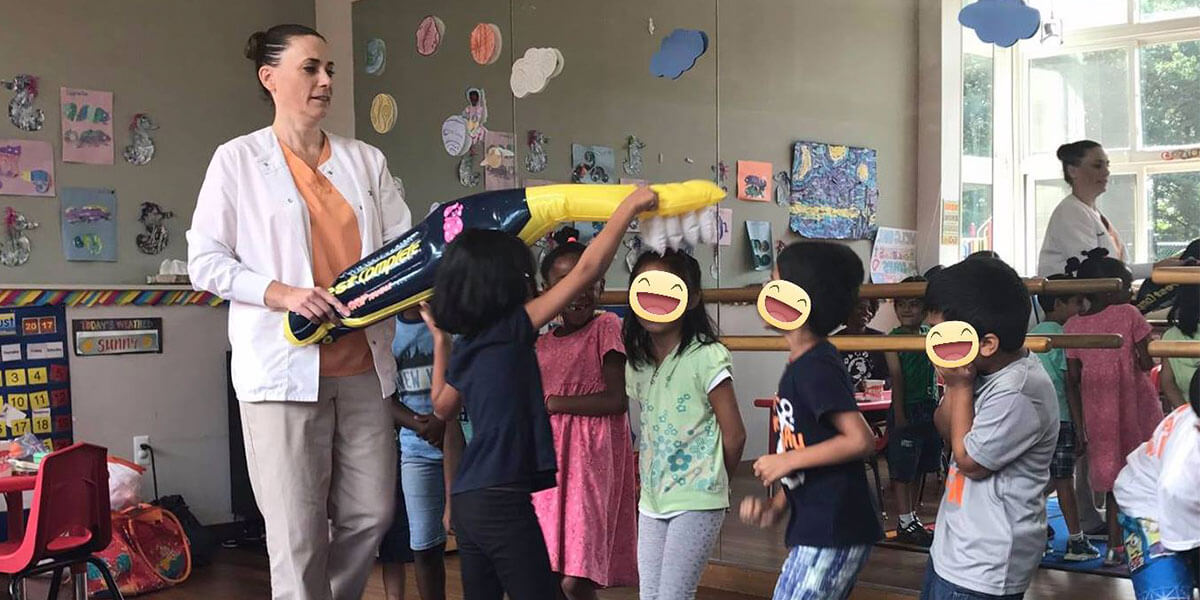 a group of children in a classroom playing with an inflatable tooth brush