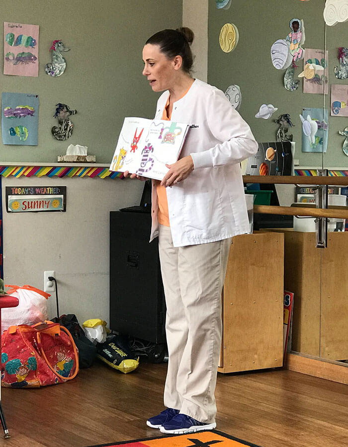 staff member in an elementary classroom reading a book in front of children