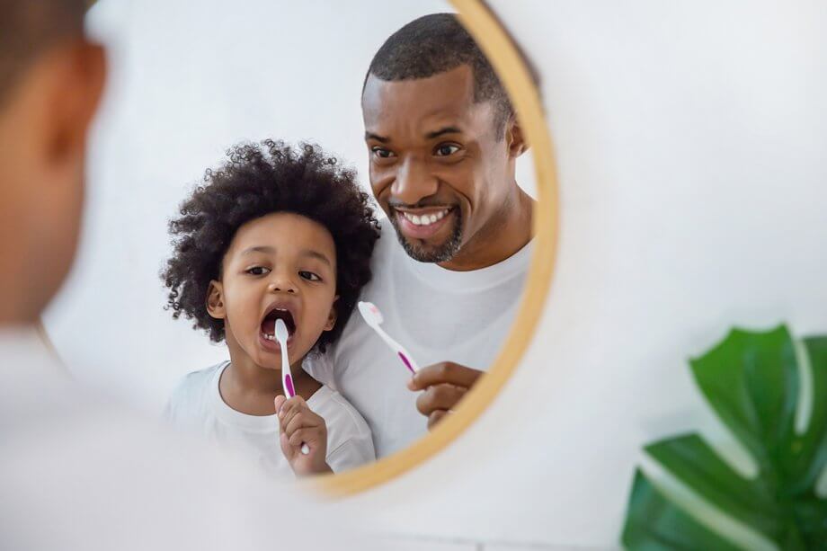 dad teaches toddler how to brush teeth