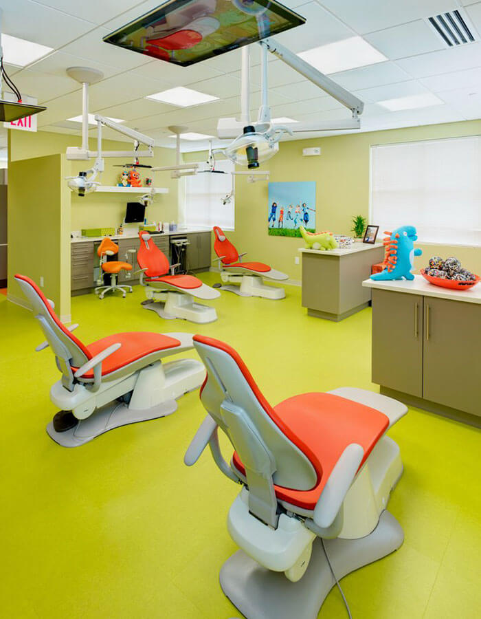 green dental examination room with orange and white chairs with toy dinosaurs on counter