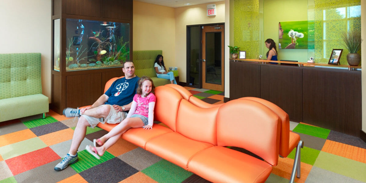 dental waiting room with large orange seating, green chairs, and multi-colored floor