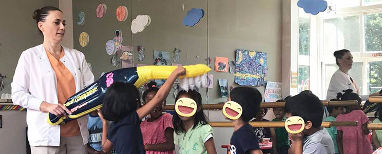 a group of children in a classroom playing with an inflatable tooth brush
