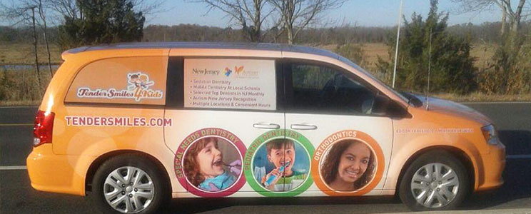 minivan wrapped in orange with Tender Smiles 4 Kids logo and dental information