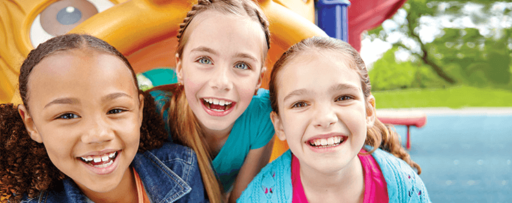 three smiling adolescent girls on a playground