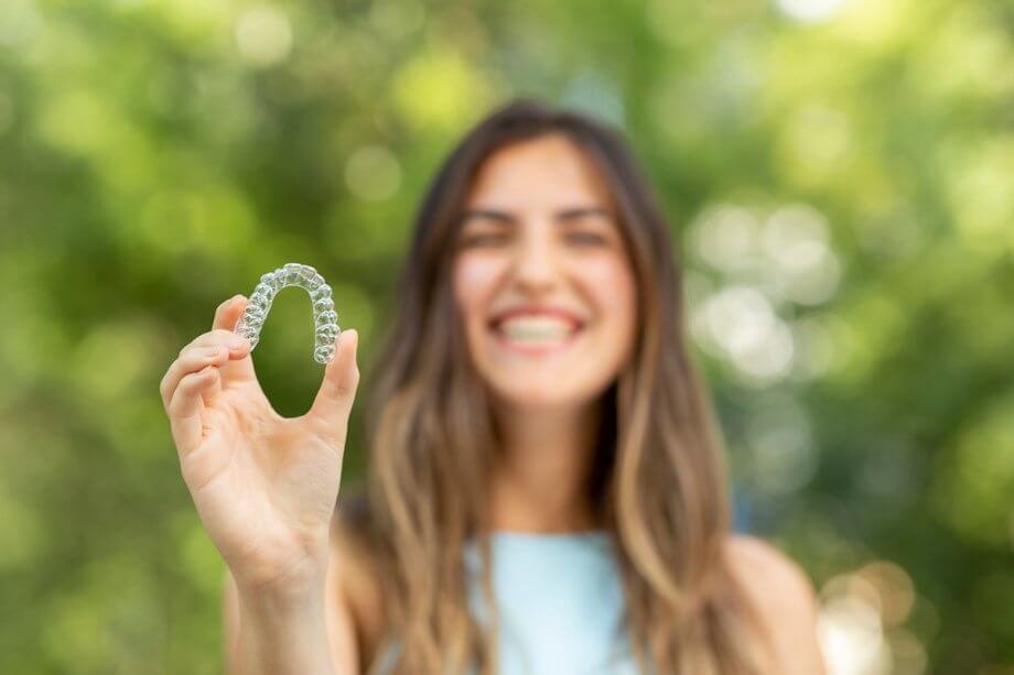 a woman holds an Invisalign aligner